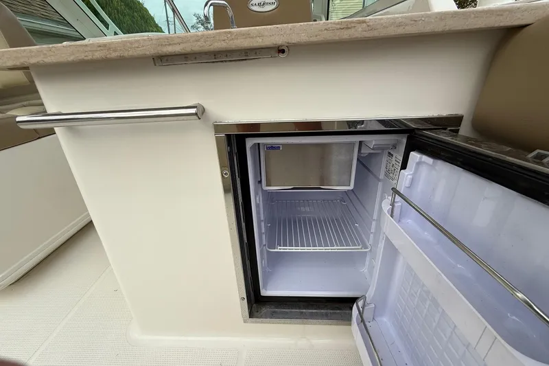 Slide: The Image of Open mini fridge on 2019 Sailfish 275 DC boat, showcasing interior storage space. - 13