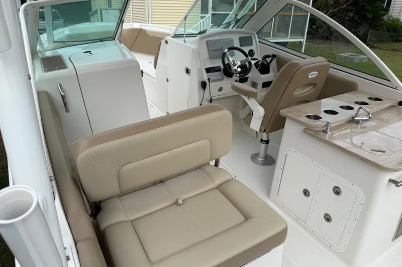 Slide: The Image of 2019 Sailfish 275 DC boat interior with beige seating, steering console, and kitchenette. - 28