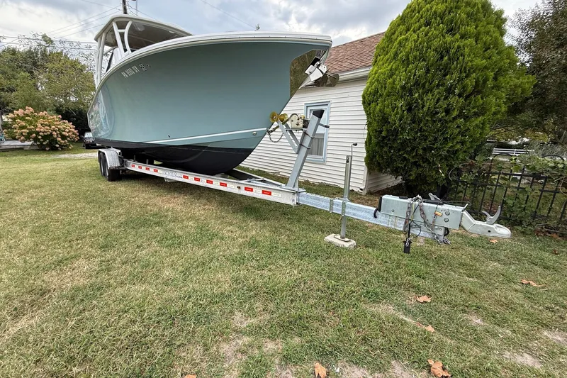 Slide: The Image of 2019 Sailfish 275 DC boat on trailer, parked on grass near a house. - 5