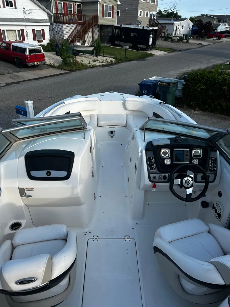 Slide: The Image of 2008 Chaparral Sunesta 244 boat interior with steering wheel and seating, parked in a residential area. - 21