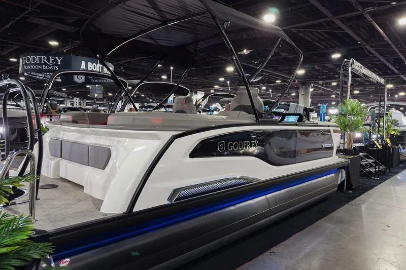 Slide: The Image of 2026 Godfrey Sanpan 23' Split Bench pontoon boat displayed at an indoor boat show. - 2