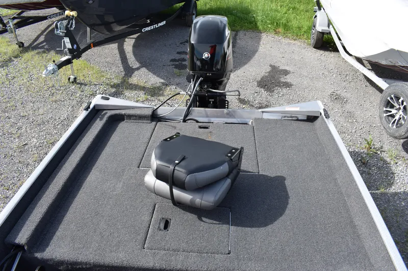 Slide: The Image of 2025 Crestliner 1700 Storm boat with folded seat on carpeted deck, parked outdoors. - 8