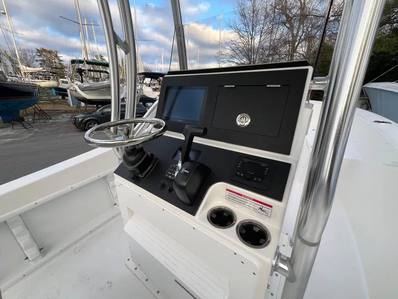 Slide: The Image of 2024 KenCraft 21 boat console with steering wheel and controls, docked in a marina. - 7