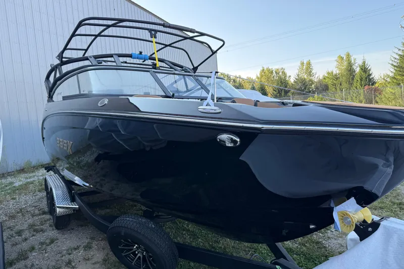 Slide: The Image of 2026 Yamaha Boats 255XD in black, parked on a trailer near a building. - 2