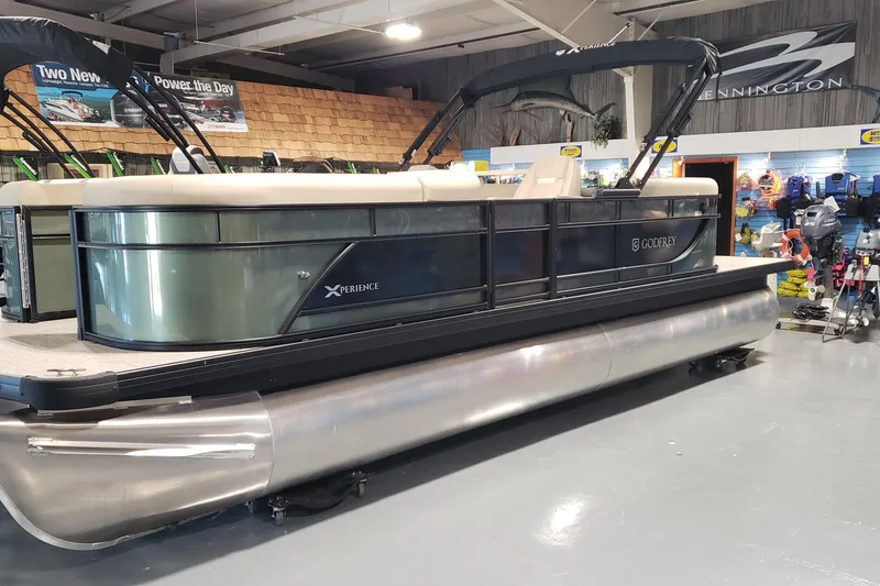 The Image of 2026 Sweetwater EX2286SBX pontoon boat displayed in a showroom with accessories. - 0