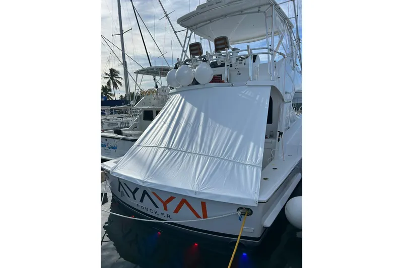 Slide: The Image of 2005 Hatteras 50 Convertible yacht docked, featuring a covered deck and visible name "AYAYA." - 105