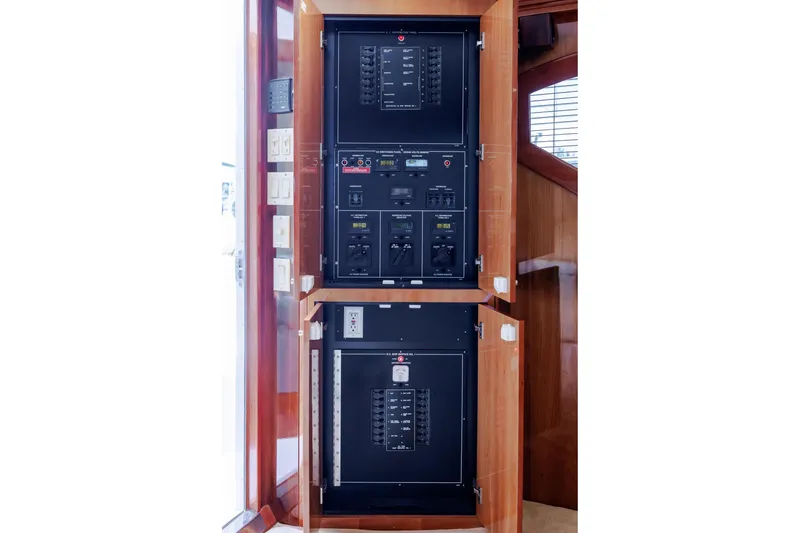Slide: The Image of Electrical panel inside 2005 Hatteras 50 Convertible yacht, featuring wooden cabinetry. - 28