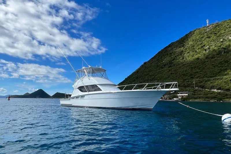 Slide: The Image of 2005 Hatteras 50 Convertible yacht anchored in scenic coastal waters. - 92