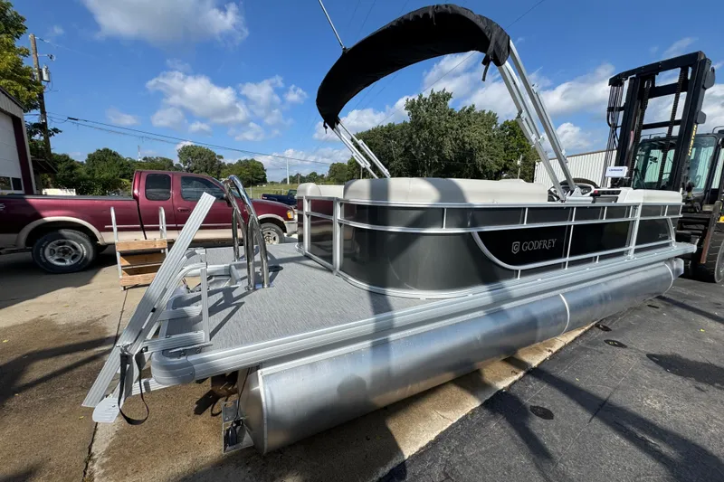 Slide: The Image of 2026 Sweetwater EX2286SBX pontoon boat with canopy, parked outdoors on a sunny day. - 2