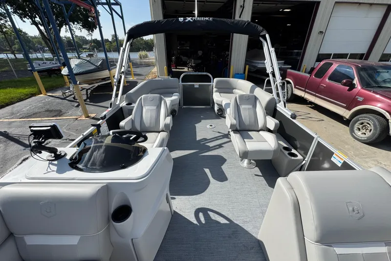 Slide: The Image of 2026 Sweetwater EX2286SBX pontoon boat with modern seating and steering console, docked outdoors. - 8