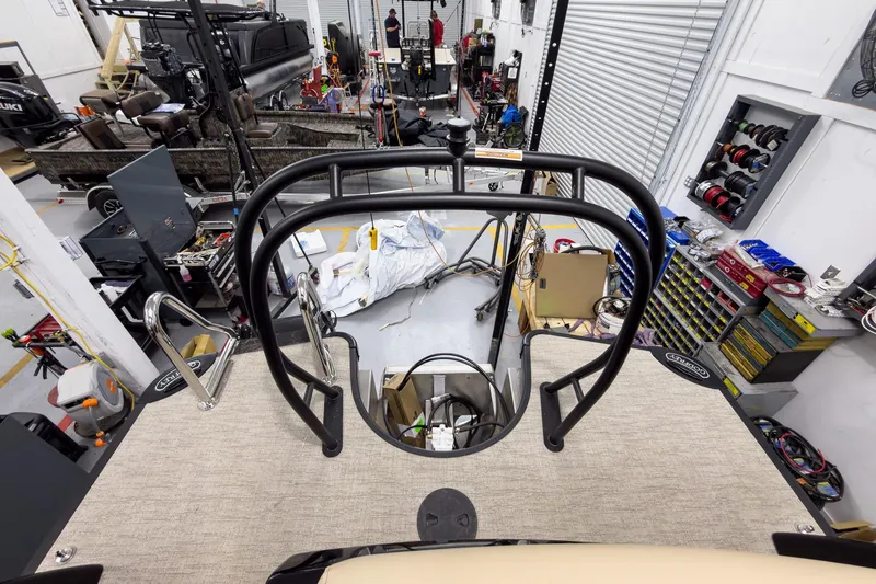 Slide: The Image of 2026 Godfrey Sanpan 23' Ultra Lounge Tritoon in workshop, surrounded by tools and equipment. - 41