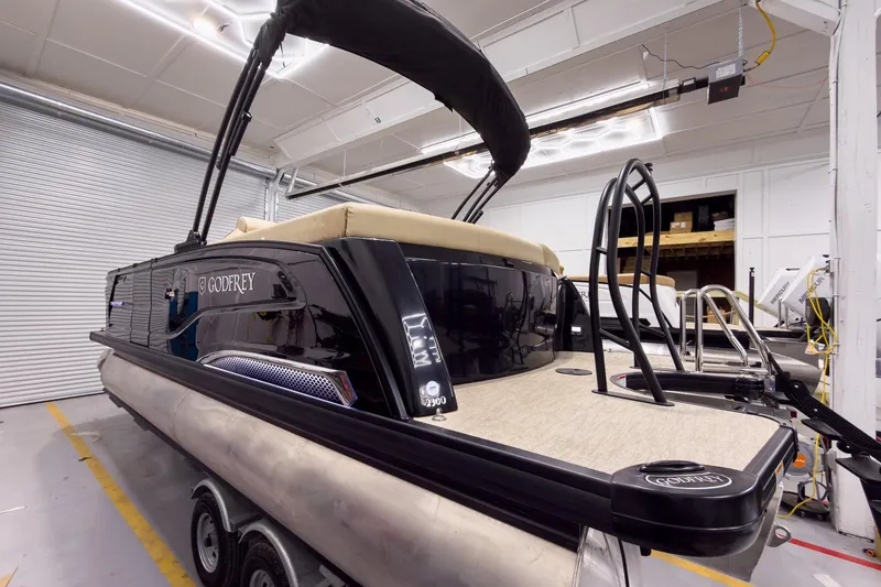 Slide: The Image of 2026 Godfrey Sanpan 23' Ultra Lounge Tritoon in a showroom, showcasing sleek design and luxury features. - 5