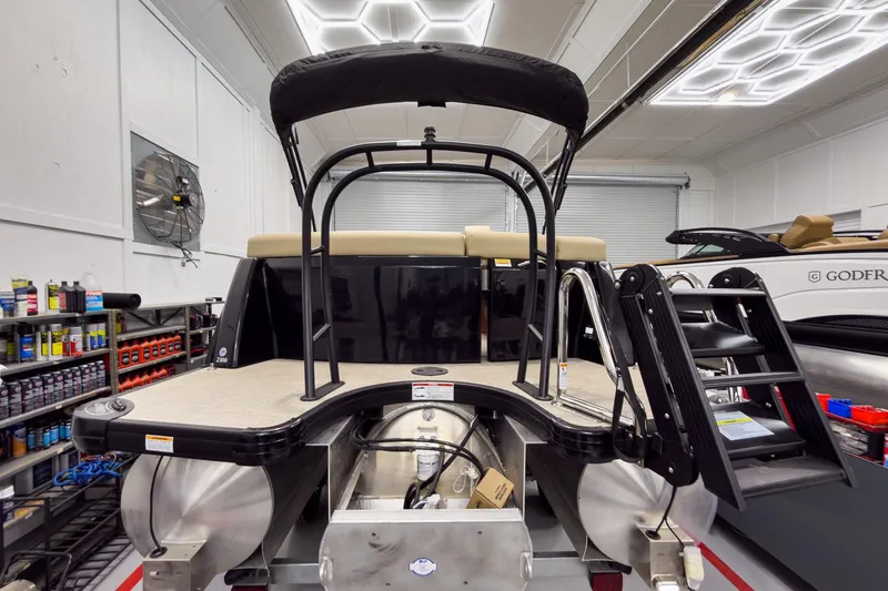 Slide: The Image of 2026 Godfrey Sanpan 23' Ultra Lounge Tritoon in a showroom, showcasing rear deck and ladder. - 6