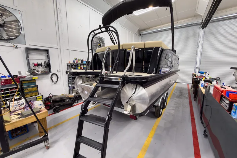 Slide: The Image of 2026 Godfrey Sanpan 23' Ultra Lounge Tritoon in workshop, showcasing rear view and ladder. - 7