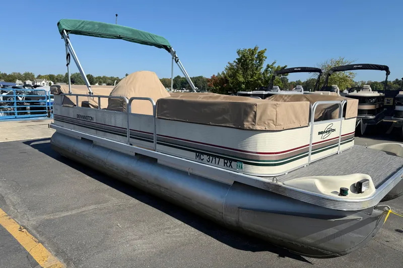 The Image of 1999 Bennington 208 L pontoon boat with green canopy and beige cover, docked outdoors. - 1