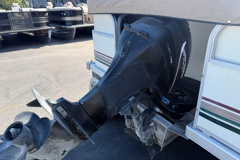 Slide: The Image of 1999 Bennington 208 L boat with an outboard motor in a parking area. - 7