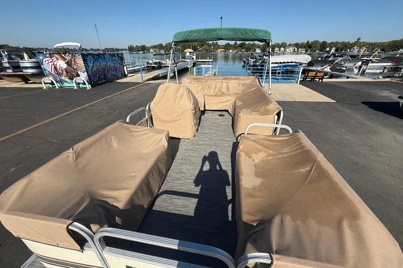 Slide: The Image of 1999 Bennington 208 L pontoon boat with covered seats at a marina. - 8