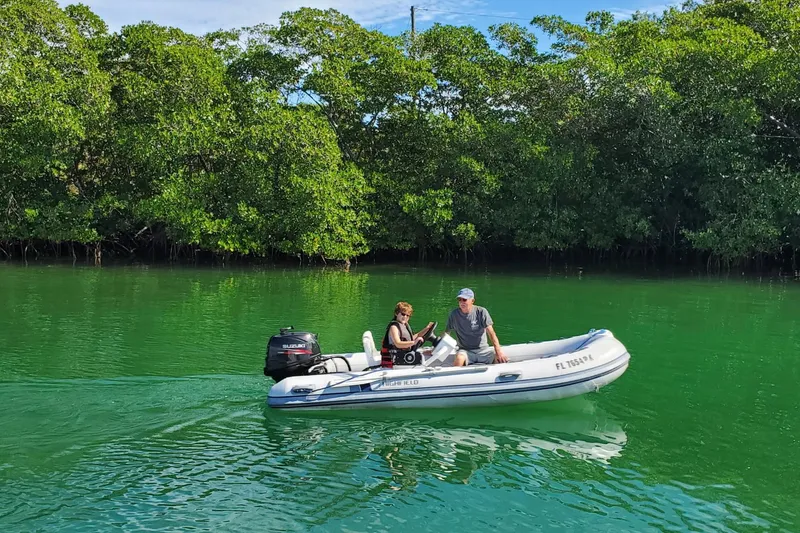 Slide: The Image of Two people in a small boat on green water near lush mangroves. - 10