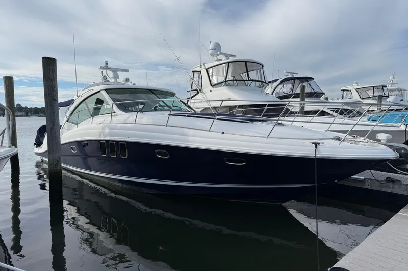 Slide: The Image of 2006 Sea Ray 48 Sundancer yacht docked at marina under cloudy sky. - 2