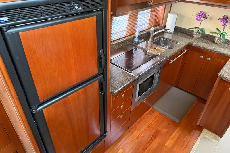 Slide: The Image of Luxurious kitchen interior of 2006 Sea Ray 48 Sundancer yacht with wood cabinetry and modern appliances. - 51