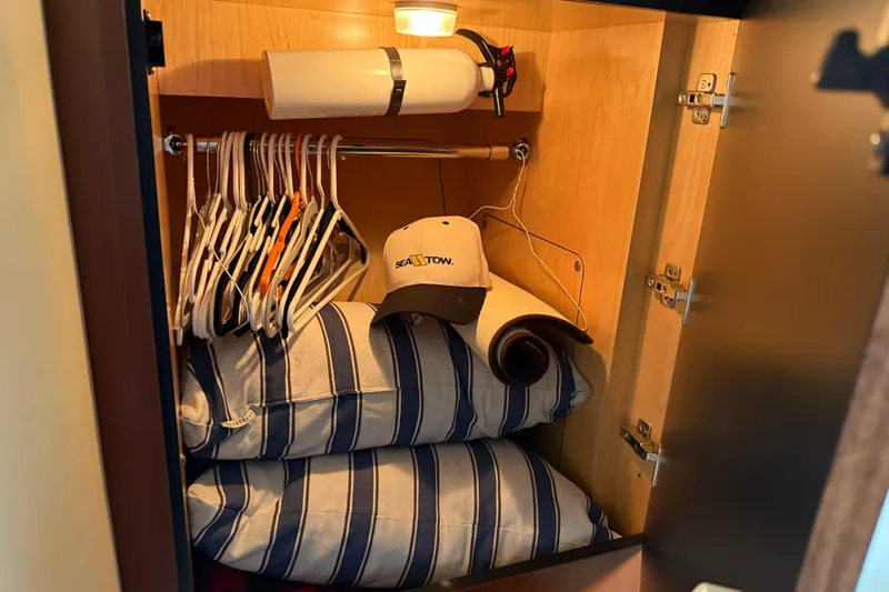 Slide: The Image of Cabinet in 2006 Sea Ray 48 Sundancer with hangers, striped pillows, and a cap. - 70