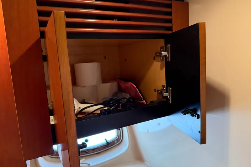 Slide: The Image of Open cabinet in 2006 Sea Ray 48 Sundancer yacht, showing storage items and window reflection. - 80
