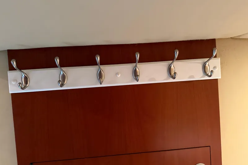 Slide: The Image of Wall-mounted coat hooks on a wooden panel inside a 2006 Sea Ray 48 Sundancer yacht. - 89