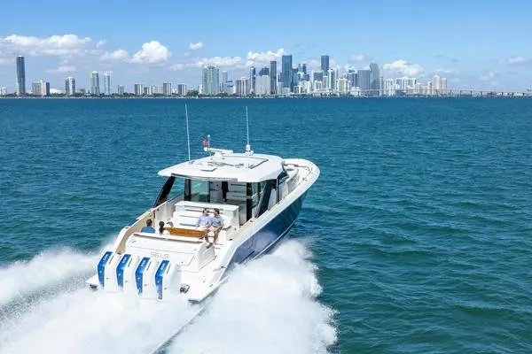 Slide: The Image of 2025 Tiara Yachts 56 LS cruising on blue waters with city skyline in background. - 4
