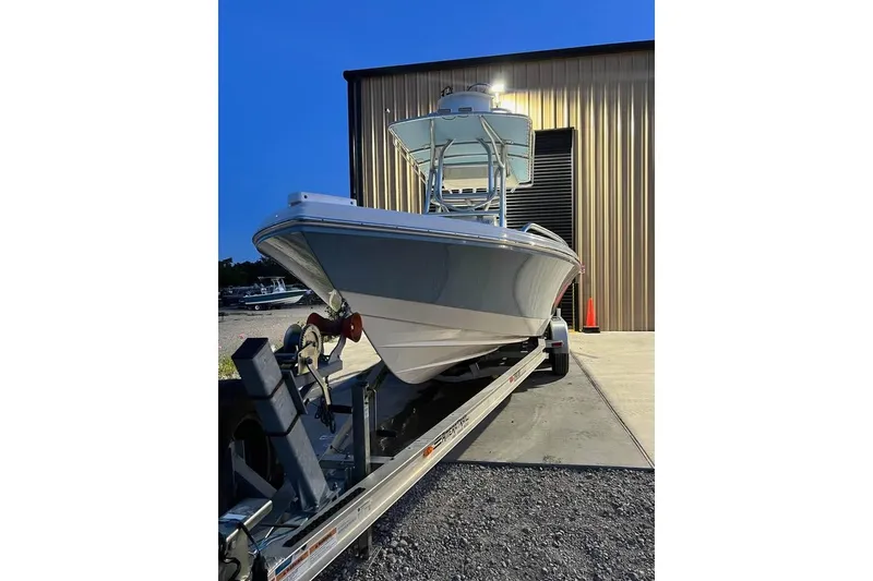 Slide: The Image of 2023 Pathfinder 2600 HPS boat on trailer, parked outside a metal building at dusk. - 6