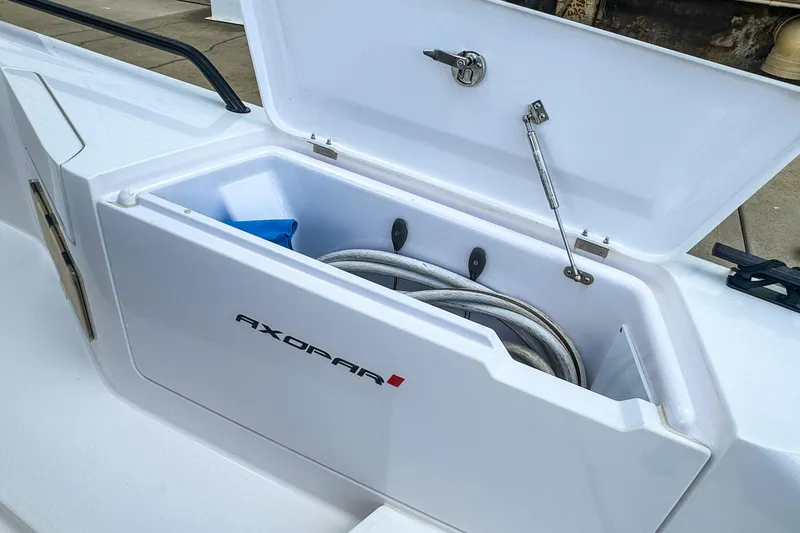 Slide: The Image of Open storage compartment on 2022 Axopar 37 Sun-Top boat, featuring coiled rope inside. - 13
