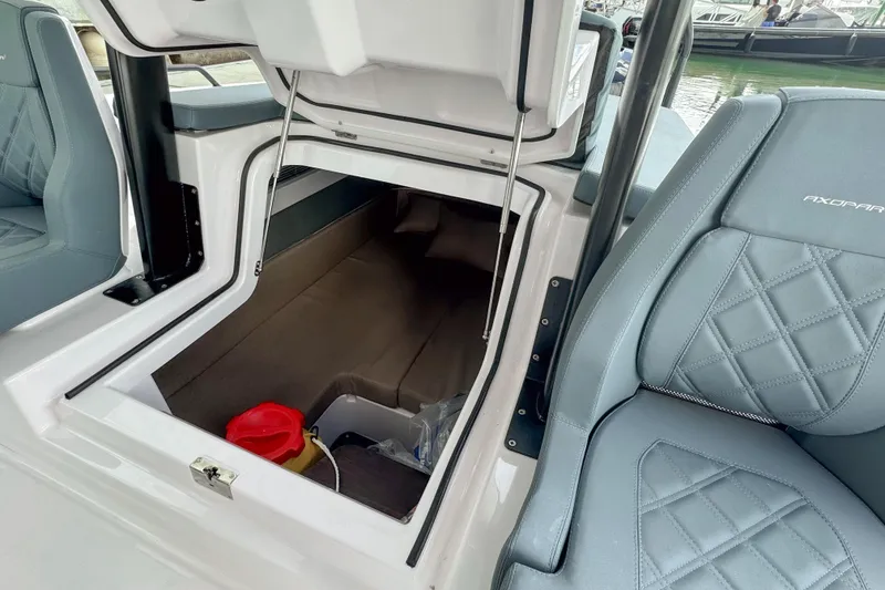 Slide: The Image of 2022 Axopar 37 Sun-Top storage compartment with open hatch and adjacent seating. - 21