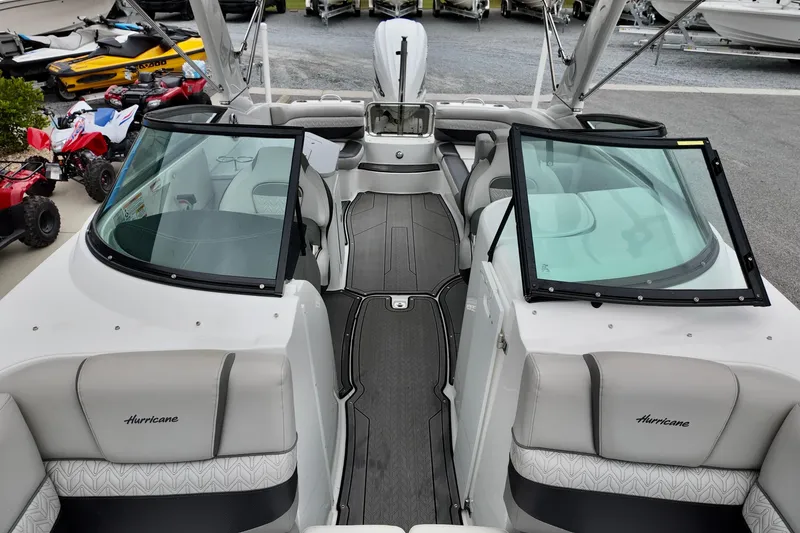 Slide: The Image of 2023 Hurricane Sun Deck 2690 boat interior with seating and windshield, parked outdoors. - 10