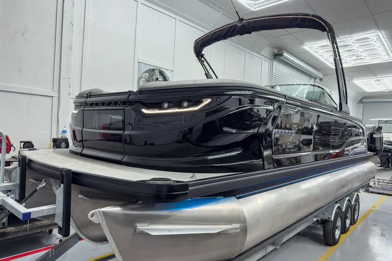 Slide: The Image of 2026 Godfrey Sanpan 27' Tritoon boat in a showroom, featuring sleek black design. - 12