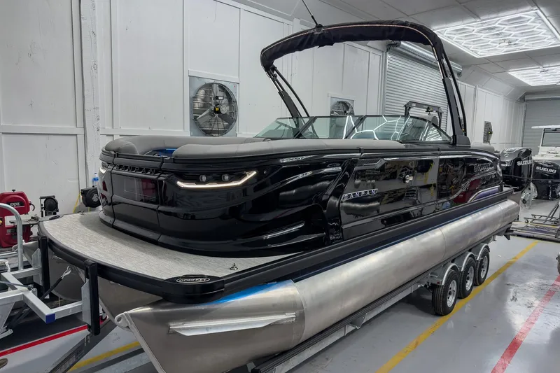 The Image of 2026 Godfrey Sanpan 27' Tritoon with twin split bench, in a showroom setting. - 2