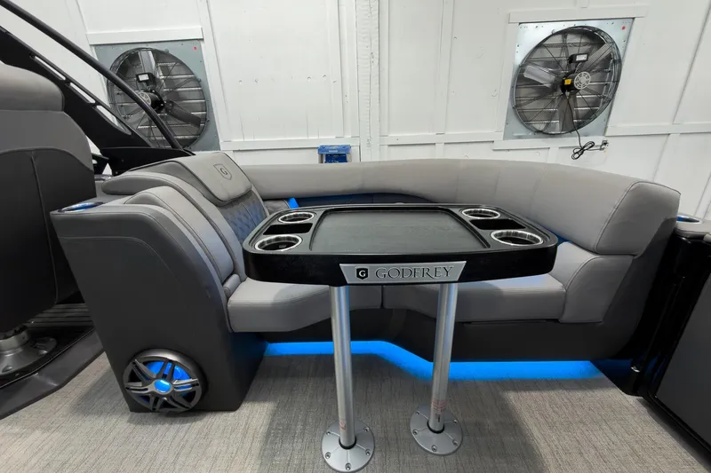 Slide: The Image of 2026 Godfrey Sanpan 27' Tritoon interior with sleek seating and table, featuring cup holders. - 36