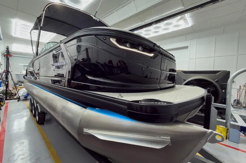 Slide: The Image of 2026 Godfrey Sanpan 27' Tritoon boat in a workshop, showcasing sleek design and modern features. - 4