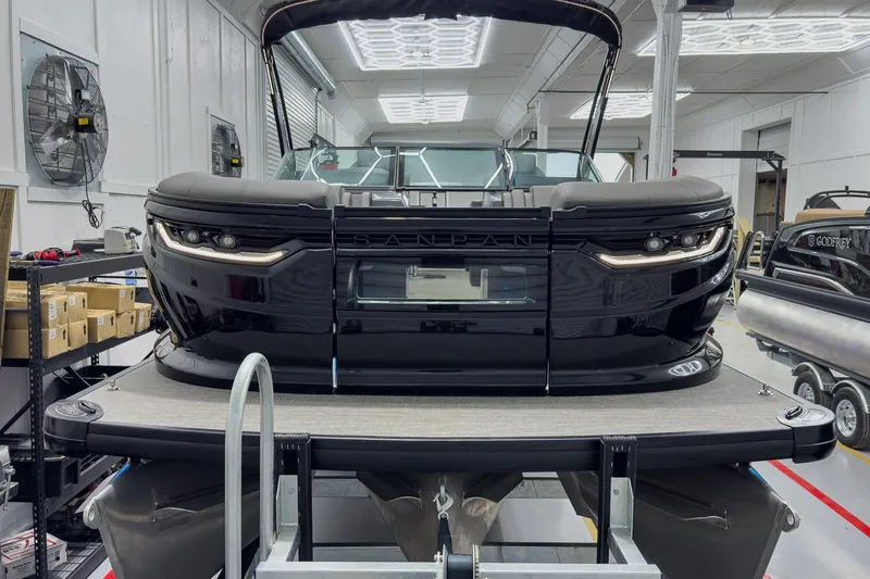 Slide: The Image of 2026 Godfrey Sanpan 27' Tritoon in showroom, featuring sleek black design and modern amenities. - 8