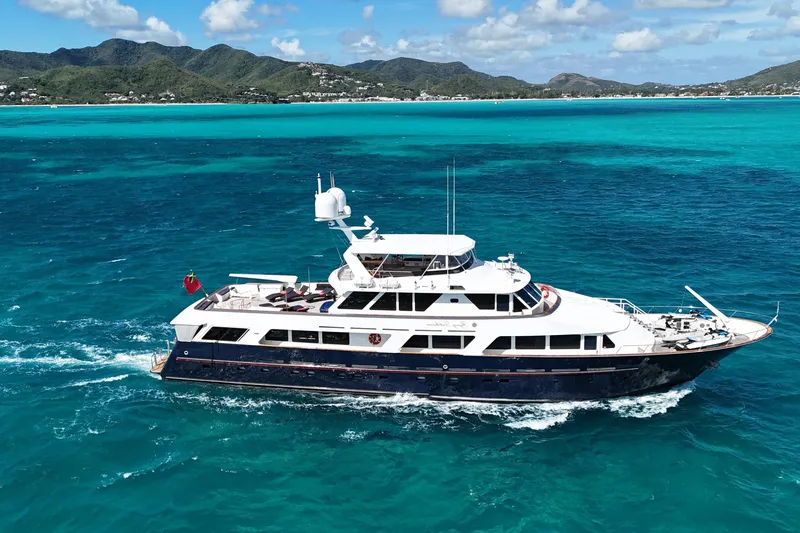 The Image of Luxurious 1984 Lloyds Ships Tri-Deck yacht cruising in turquoise waters near scenic coastline. - 0