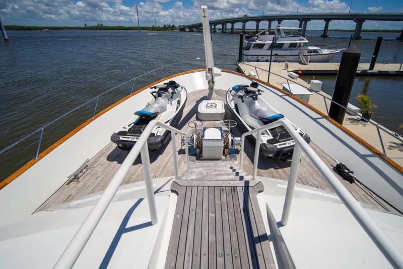 Slide: The Image of 1984 Lloyds Ships Tri-Deck yacht with jet skis on deck, docked near a bridge. - 4