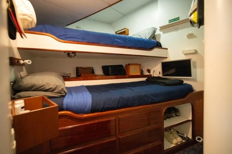 Slide: The Image of Cozy cabin with bunk beds on 1984 Lloyds Ships Tri-Deck yacht, featuring wooden storage and TV. - 53