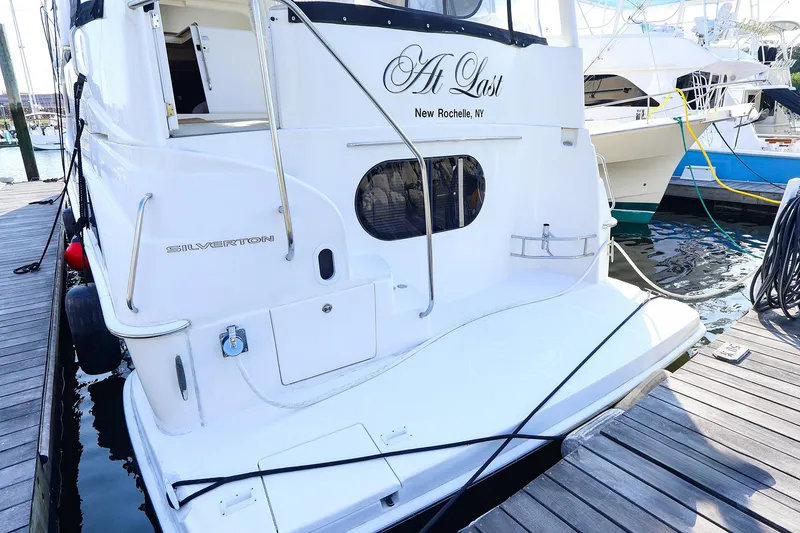 Slide: The Image of 2002 Silverton 43 Motor Yacht docked, featuring sleek design and "At Last" nameplate. - 2