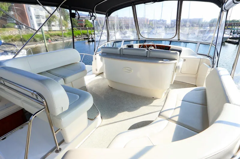 Slide: The Image of 2002 Silverton 43 Motor Yacht interior with spacious seating and helm, docked at marina. - 7