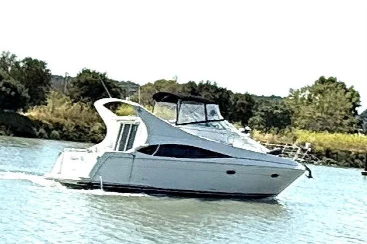 Slide: The Image of 2007 Carver 36 Mariner yacht cruising on a serene lake with lush greenery. - 2