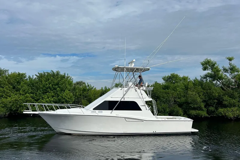 The Image of 2008 Cabo Yachts Sportfish 35 cruising on a calm waterway, surrounded by lush greenery. - 0