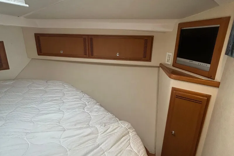 Slide: The Image of 2008 Cabo Yachts Sportfish 35 cabin interior with bed, TV, and wooden storage cabinets. - 11