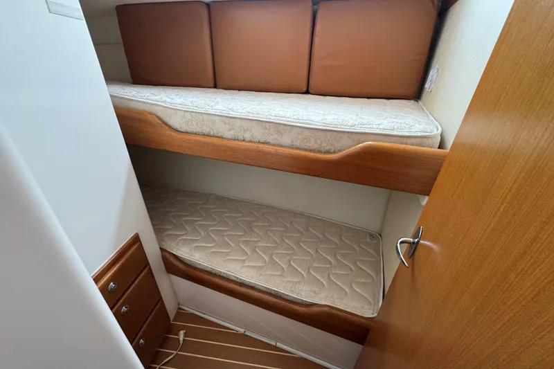 Slide: The Image of 2008 Cabo 35 Flybridge cabin with wooden bunk beds and beige mattresses. - 12
