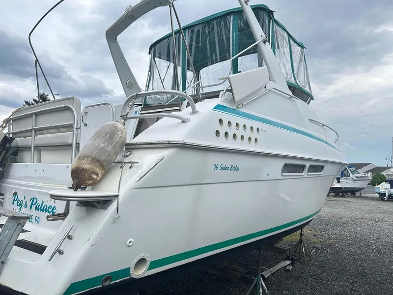 Slide: The Image of 1993 Mainship 36 Express boat on land, white with teal accents, cloudy sky background. - 20