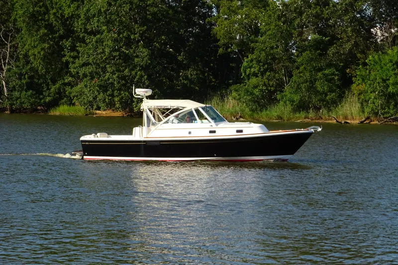 Slide: The Image of 2007 Hunt Yachts Surfhunter 29 cruising on a serene lake with lush greenery. - 2