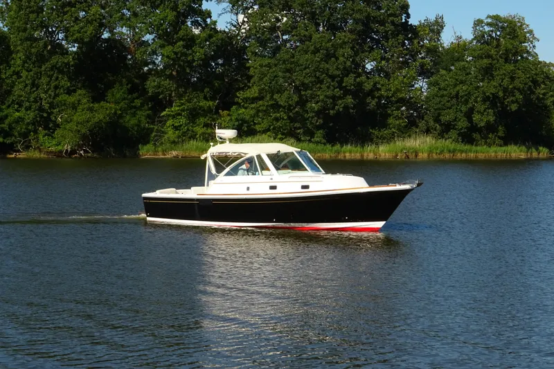 Slide: The Image of 2007 Hunt Yachts Surfhunter 29 cruising on a serene lake with lush green trees. - 3