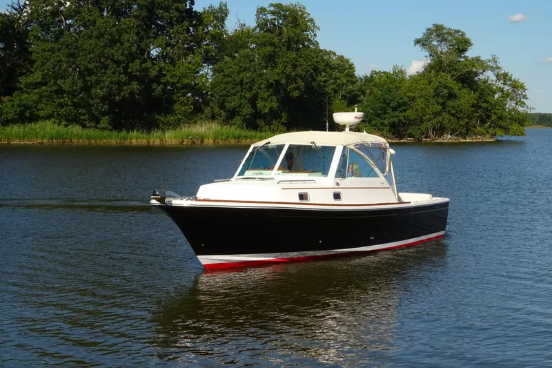 Slide: The Image of 2007 Hunt Yachts Surfhunter 29 cruising on a serene lake with lush greenery. - 4